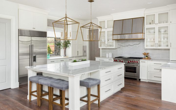 Bright and airy modern kitchen with white cabinets, marble countertops, and chic gold hanging lights over the island, perfect for gourmet cooking.