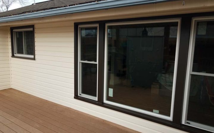 Modern home deck area with sliding glass doors and large windows, showing a partial view of the interior.